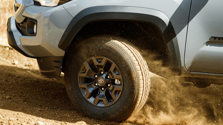 The front left tire of a 2021 Toyota Tacoma kicking up dirt while driving off-road