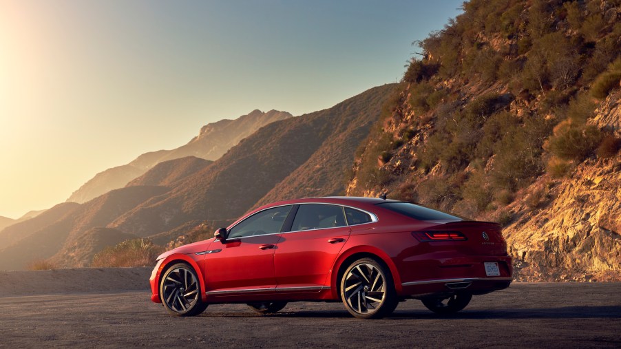 A red 2021 Volkswagen Arteon sedan parked in front of mountains on a sunny day
