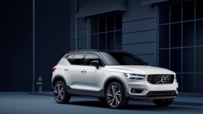 A 2021 Volvo XC40 R-Design in Crystal White Pearl parked on a curb next to a building and fire hydrant