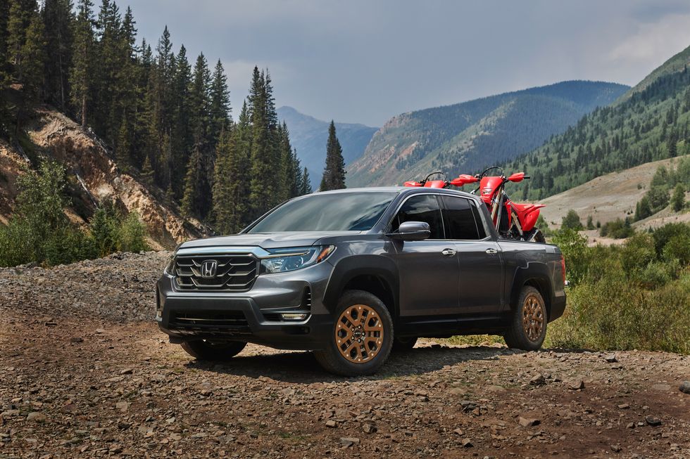 a new Honda Ridgeline in the mountains with two dirt bikes on board ready for the next adventure