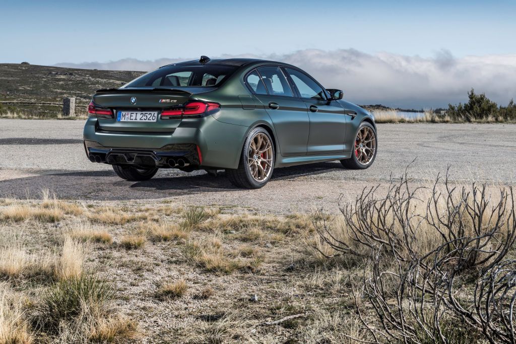 The rear 3/4 view of a matte-green 2022 BMW M5 CS on a desert hill road