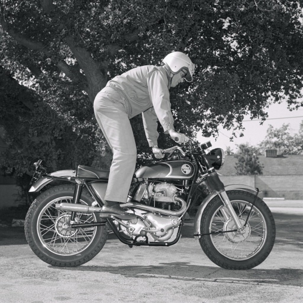 A rider using the kickstarter on a 1967 Norton P11 motorcycle