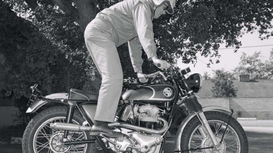 A rider using the kickstarter on a 1967 Norton P11 motorcycle