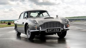 A silver Aston Martin DB5 Goldfinger Continuation on a wet track