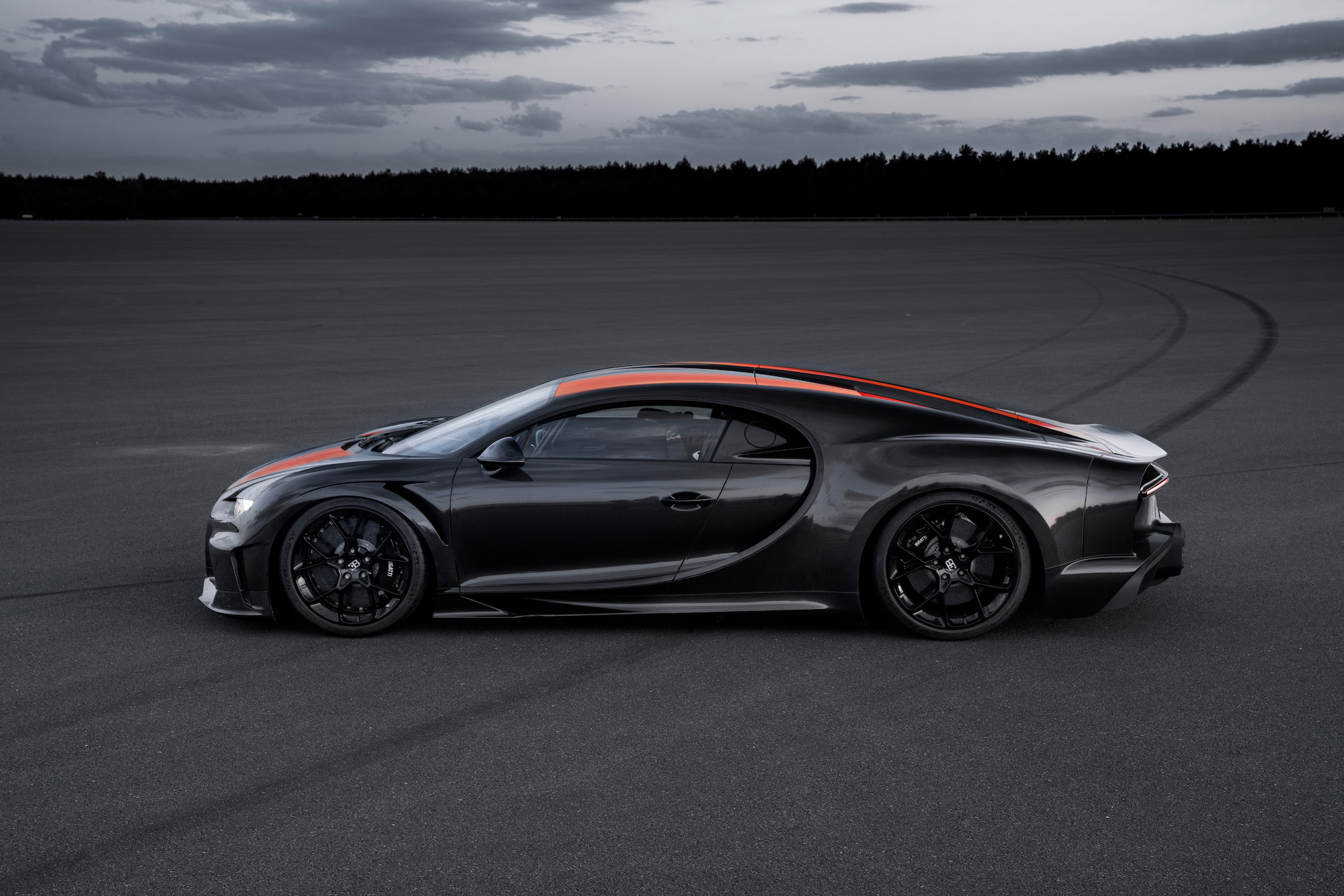 A black-and-red Bugatti Chiron Super Sport 300+ parked on a large slab of asphalt