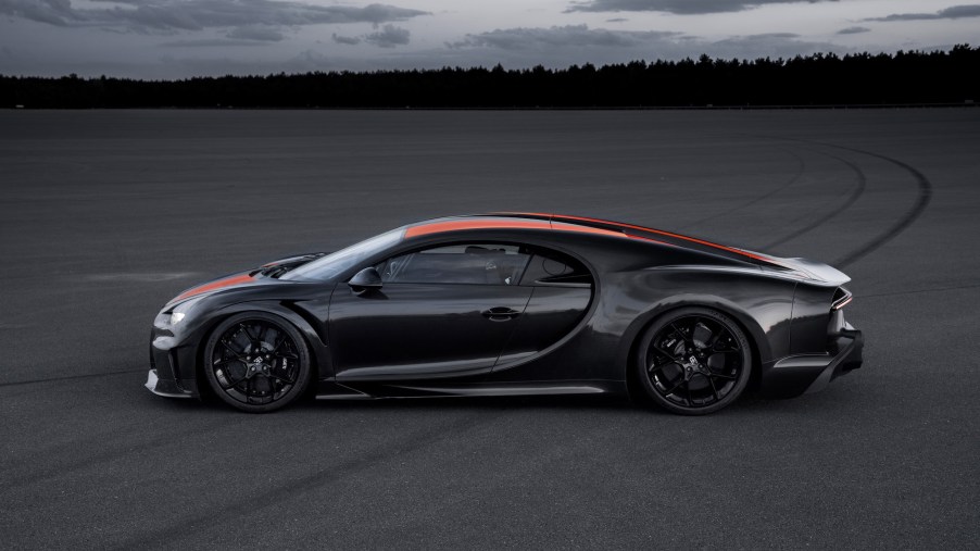 A black-and-red Bugatti Chiron Super Sport 300+ parked on a large slab of asphalt