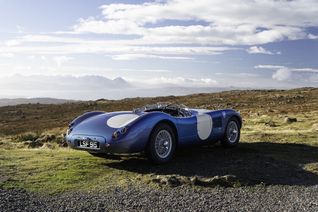 The rear 3/4 view of a blue-and-white Ecurie Ecosse LMC