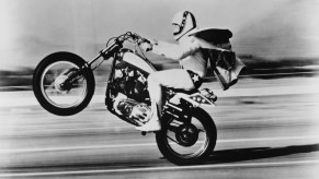 American stunt rider Evel Knievel (1938-2007) pops a wheelie on his Harley-Davidson motorcycle circa 1975