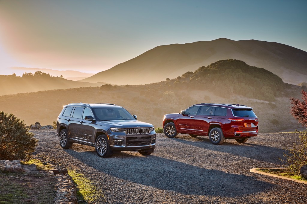 A gray-brown 2021 Jeep Grand Cherokee L Summit Reserve and a red Overland on a foggy hill
