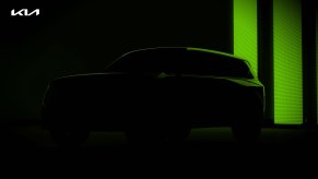 The silhouette of a forthcoming an Kia electric SUV with green lighting in the background