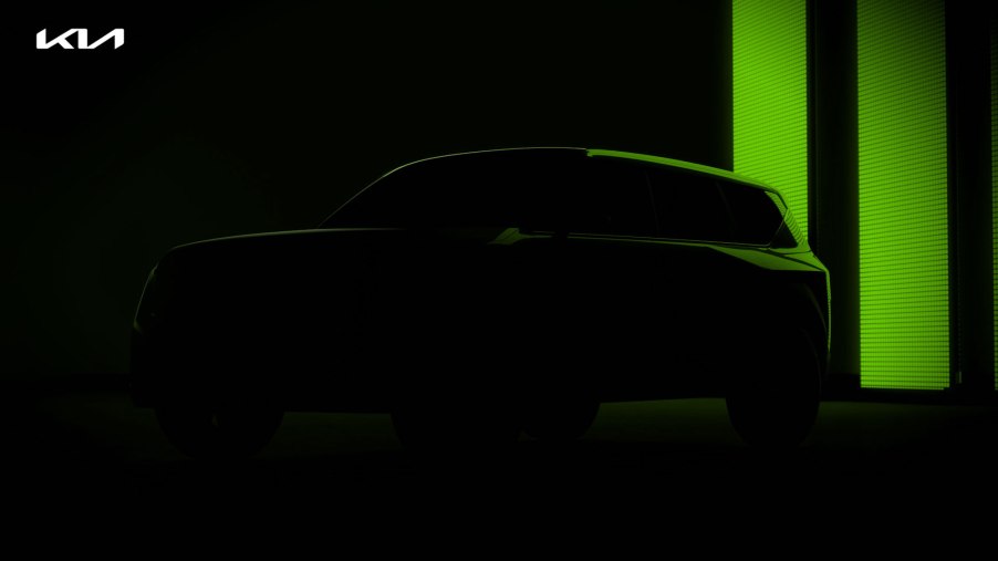 The silhouette of a forthcoming an Kia electric SUV with green lighting in the background