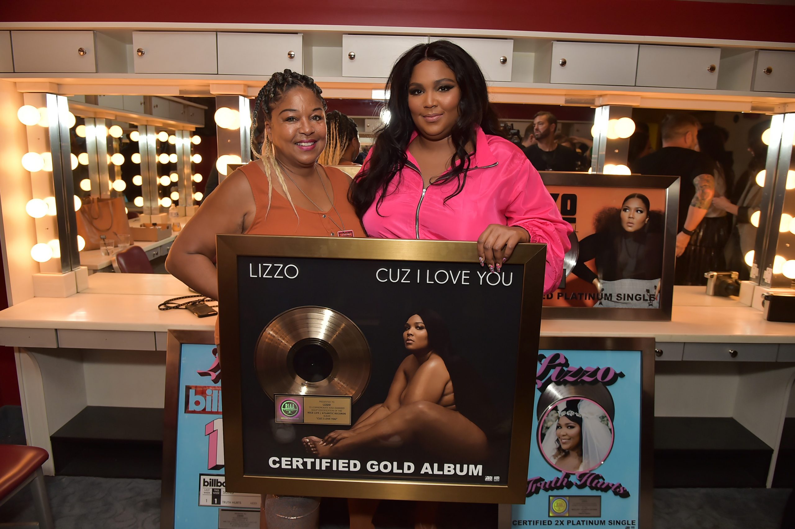 Lizzo and her mom smile proudly next to a plaque
