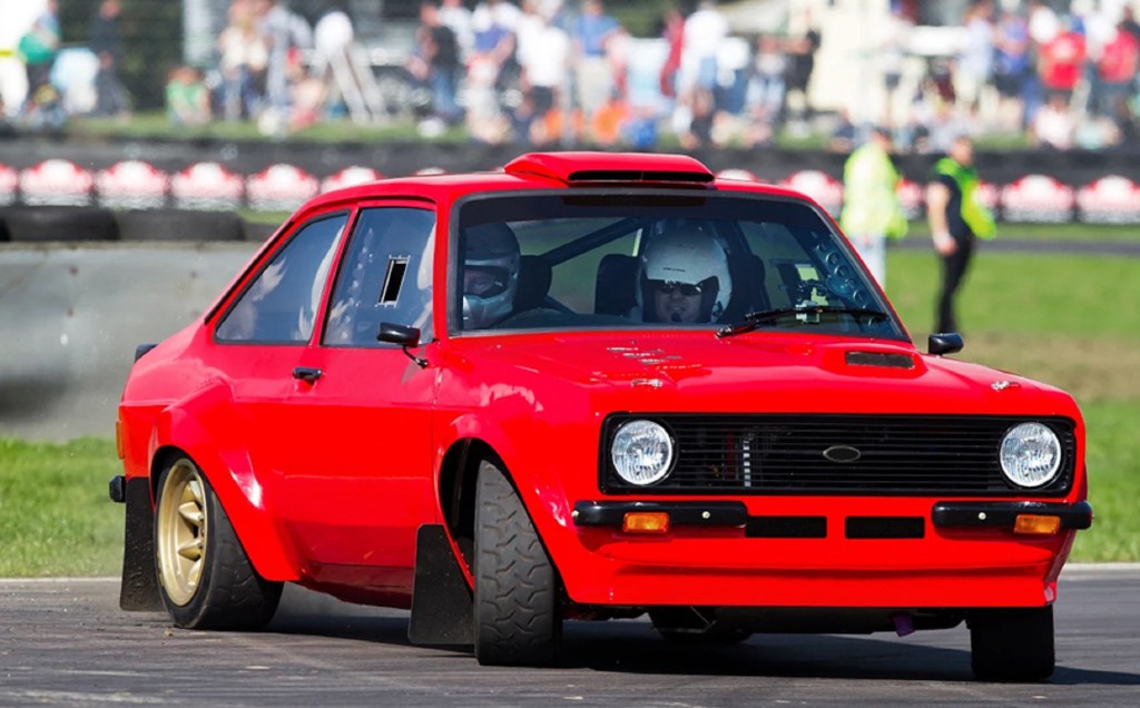 A red MST Mk2 Ford Escort Ultimate Rally Car drifts around a racetrack