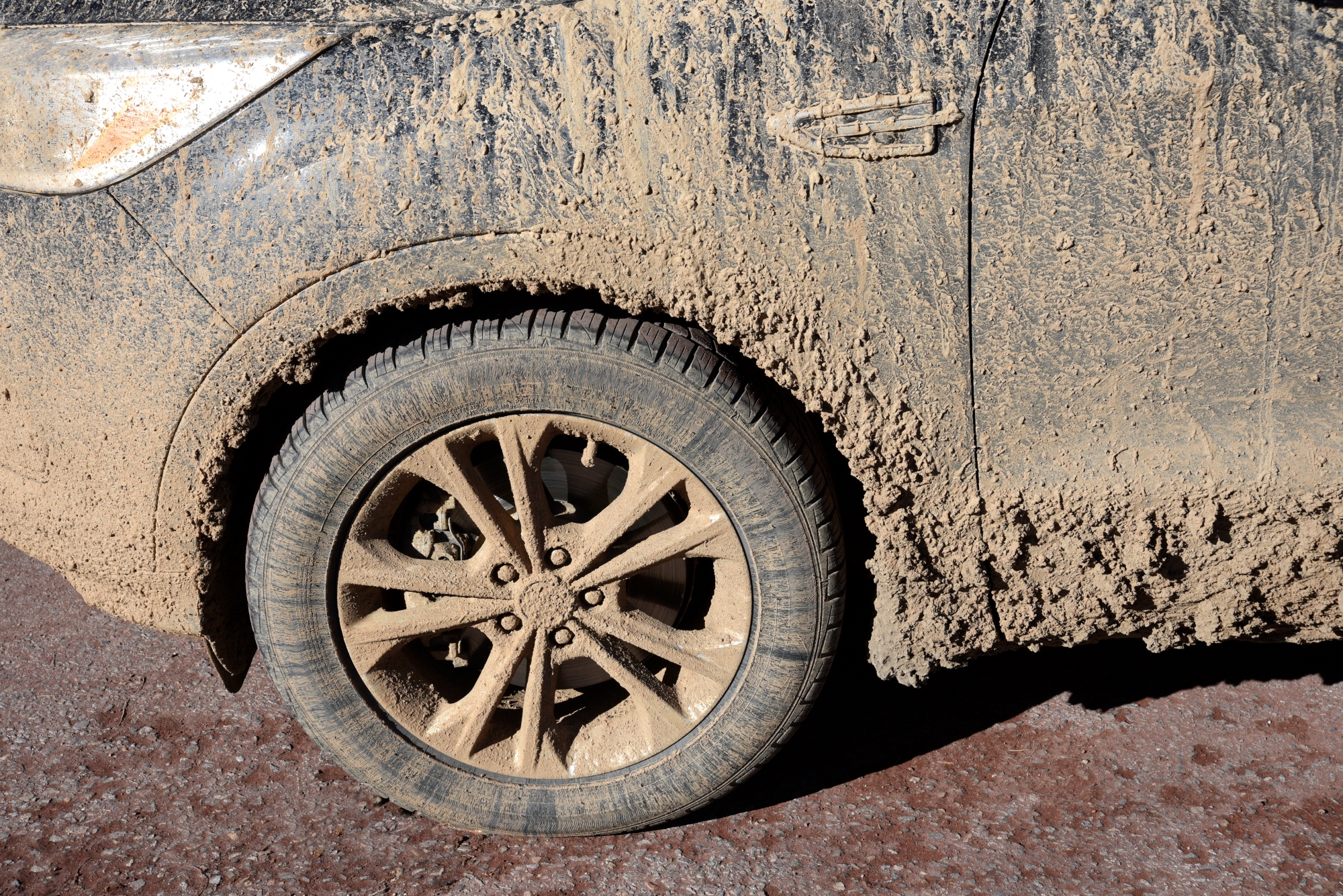 Mud is caked on the side of a car ready for detailing.