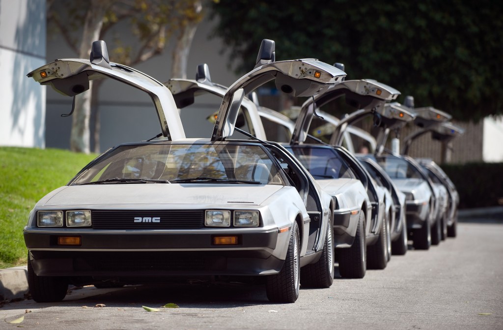DeLorean are parked in a row and all have their gullwing doors open. 