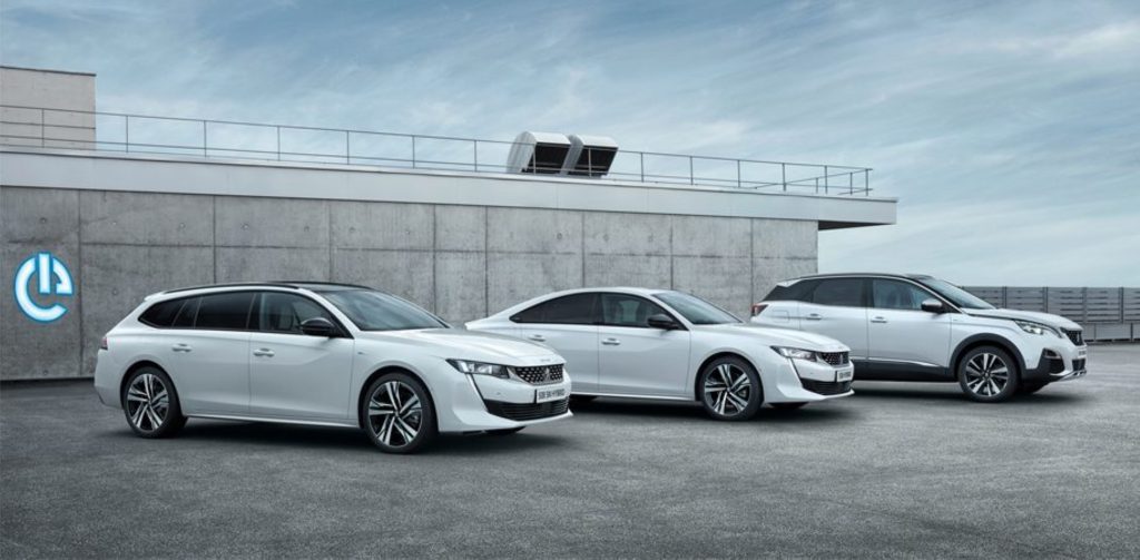 Three white Peugeot plug-in hybrid models are parked next to each other.