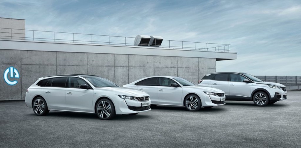 Three white Peugeot plug-in hybrid models are parked next to each other.