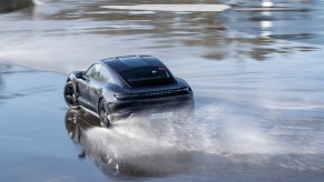 A black Porsche Taycan drifts on wet pavement