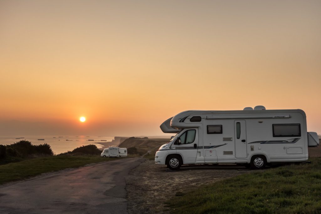 RVs parked along the coast at sunset with view over the sea.