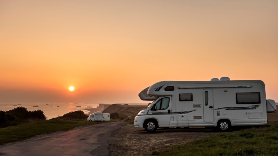 RVs parked along the coast at sunset with view over the sea.
