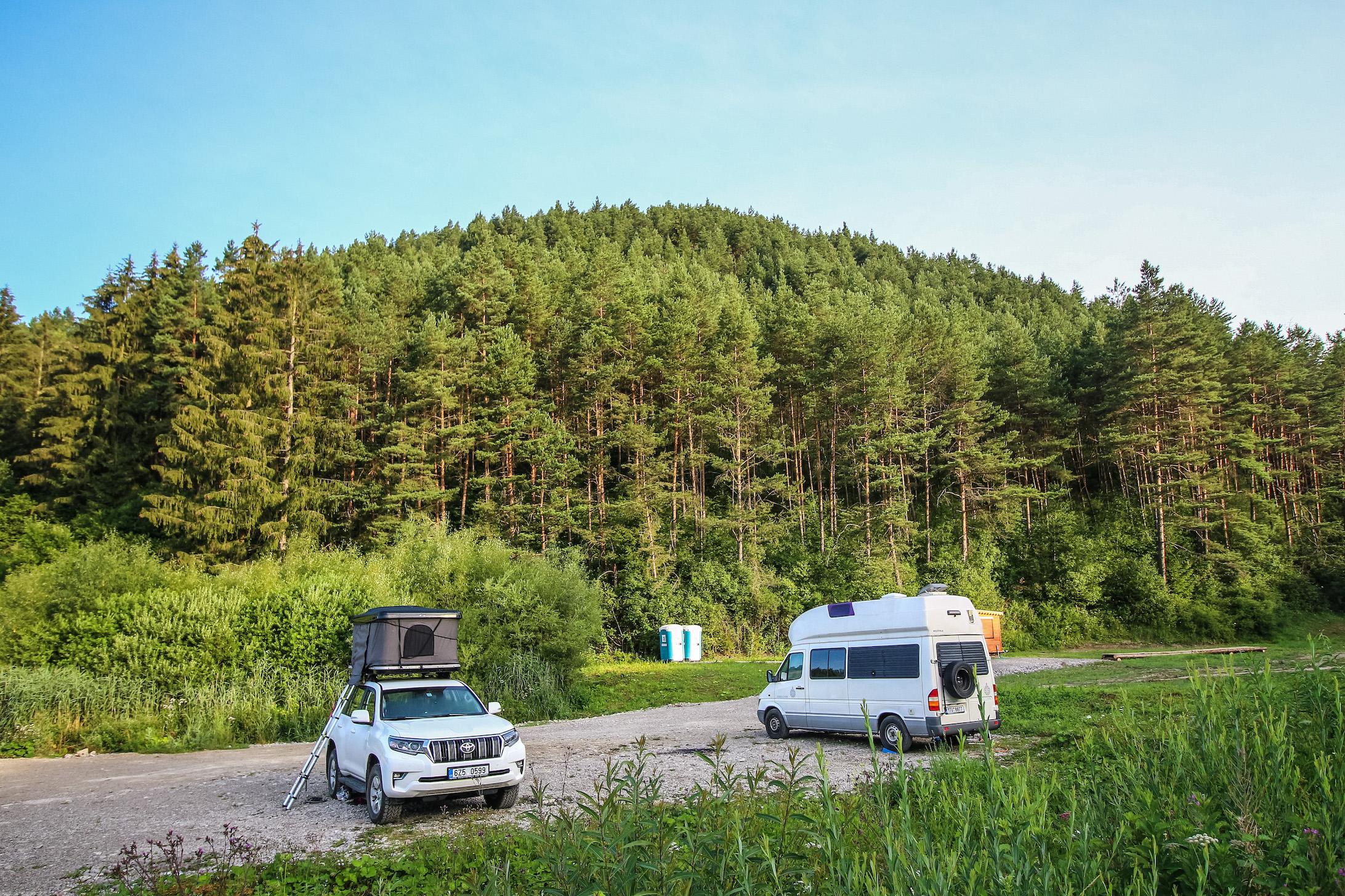 People camping in a 4x4 Toyota Landcriuser with a roof tent and Mercedes Sprinter James Cook edition RV camper van near the thermal lake Kalameny