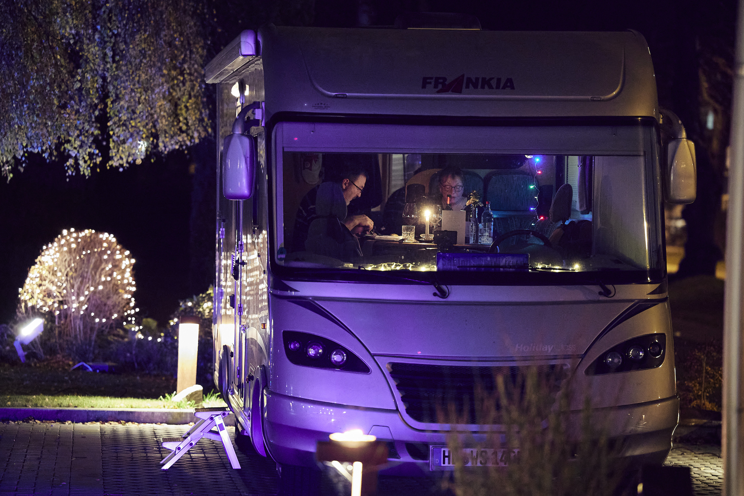 A couple enjoys the main dish of a four-course dinner in their recreational vehicle (RV) in the parking lot of the Kochschule Neumuenster cooking school