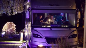 A couple enjoys the main dish of a four-course dinner in their recreational vehicle (RV) in the parking lot of the Kochschule Neumuenster cooking school