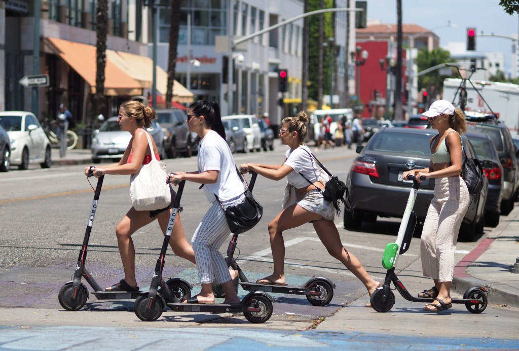 Women ride electric scooters in Santa Monica, California.