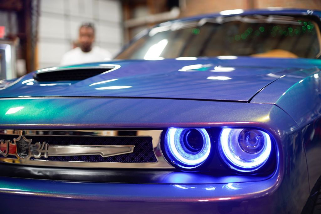 The grille of a modified violet 2017 Dodge Challenger with blue LED headlights