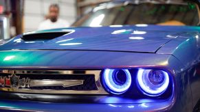 The grille of a modified violet 2017 Dodge Challenger with blue LED headlights