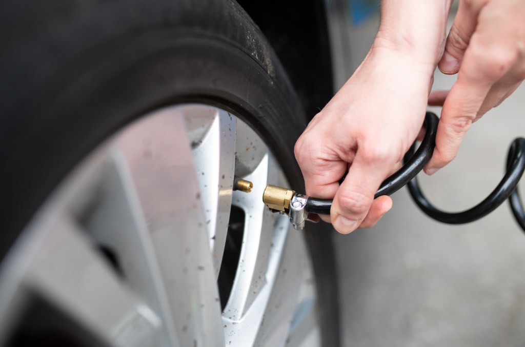 A woman checking her car's tire pressure
