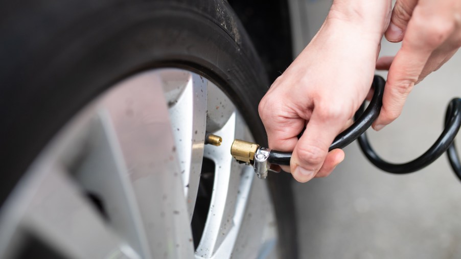 A woman checking her car's tire pressure