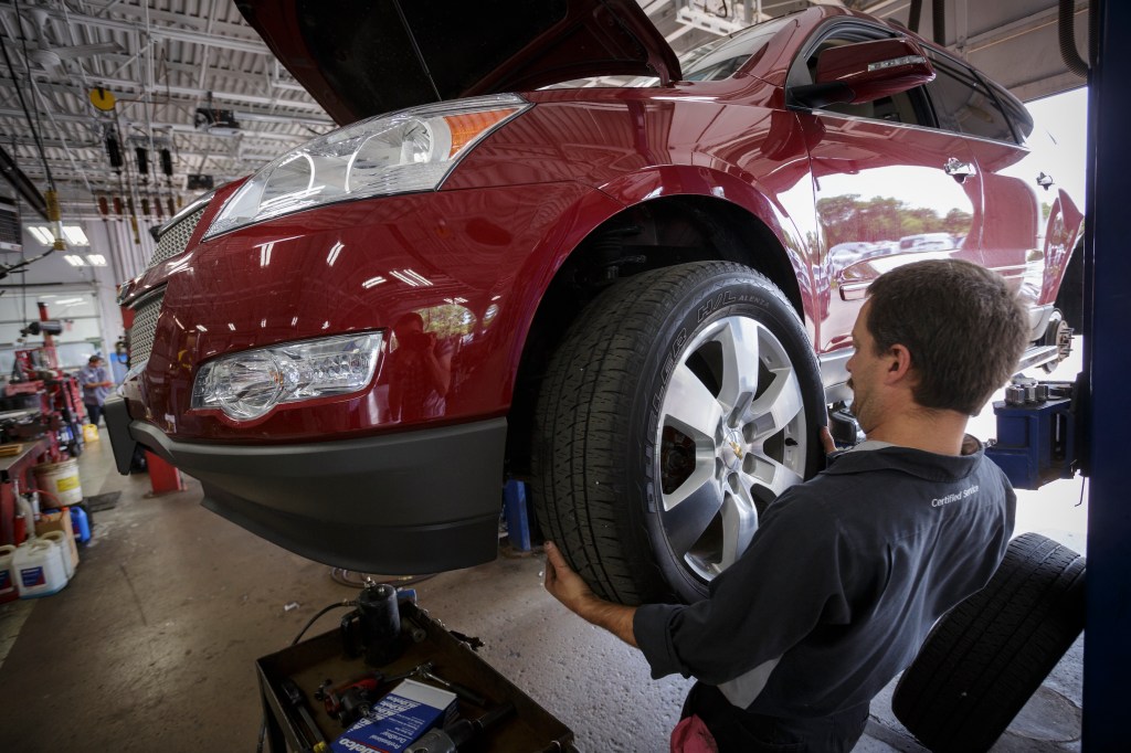 Technician Dave Serdar rotates the tires on a Chevy Traverse