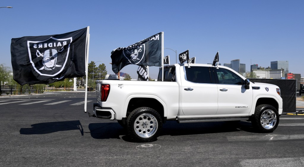 Las Vegas Raiders fans drive in a pickup truck adorned with team flags as they arrive at a parking lot at Allegiant Stadium set up for socially distanced tailgating before the NFL game between the Buffalo Bills and the Raiders