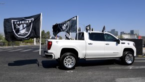 Las Vegas Raiders fans drive in a pickup truck adorned with team flags as they arrive at a parking lot at Allegiant Stadium set up for socially distanced tailgating before the NFL game between the Buffalo Bills and the Raiders