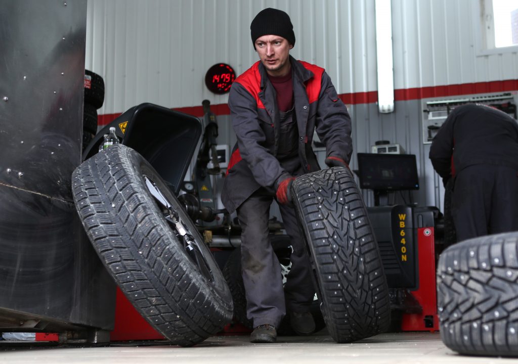 A car service worker fitting winter tires.