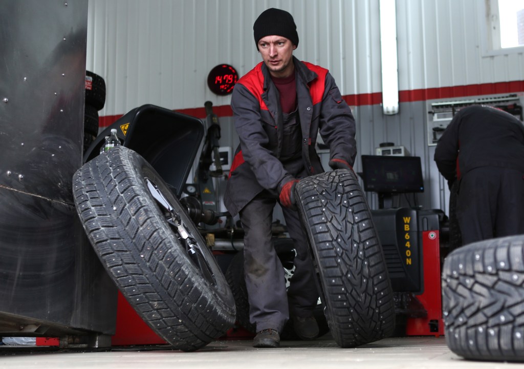  A car service worker fitting winter tires. 
