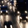 Headlights on oncoming vehicles traveling on a rain-slicked multi-lane highway