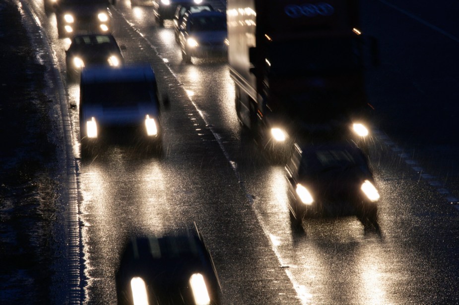 Headlights on oncoming vehicles traveling on a rain-slicked multi-lane highway