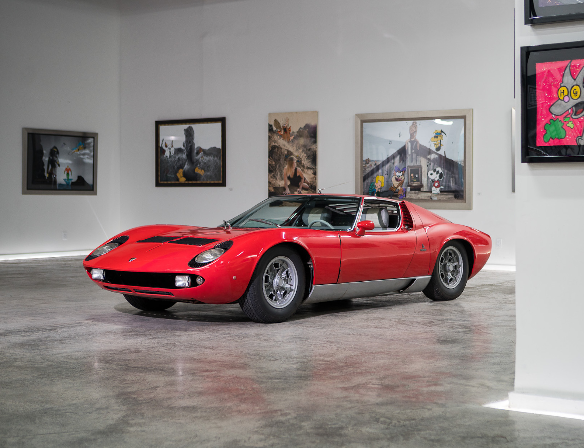 a red lamborghini Miura S parked in a gallery on display