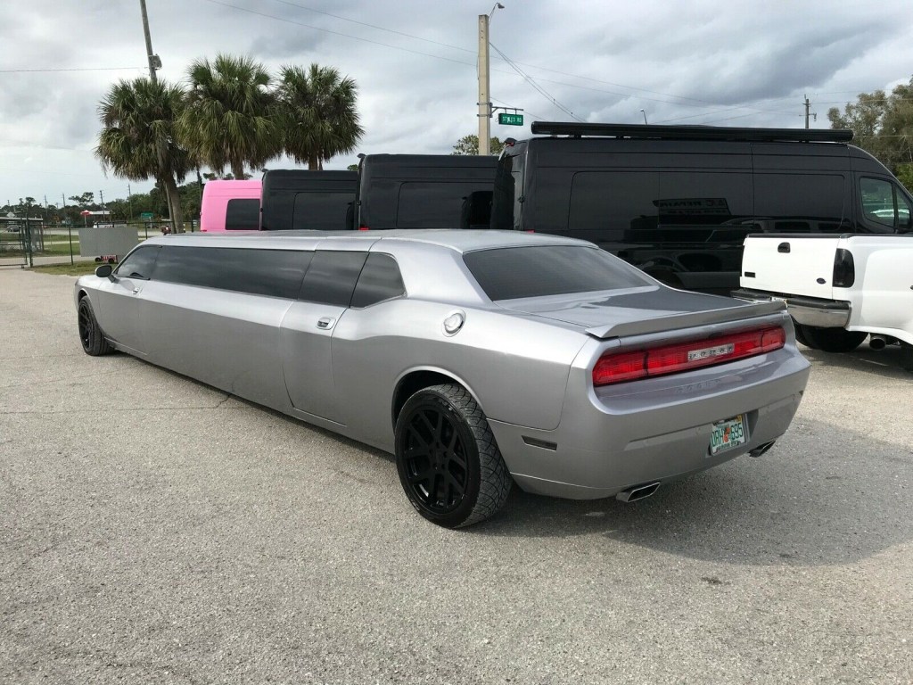 An image of a Dodge Challenger limousine outside with its doors open.