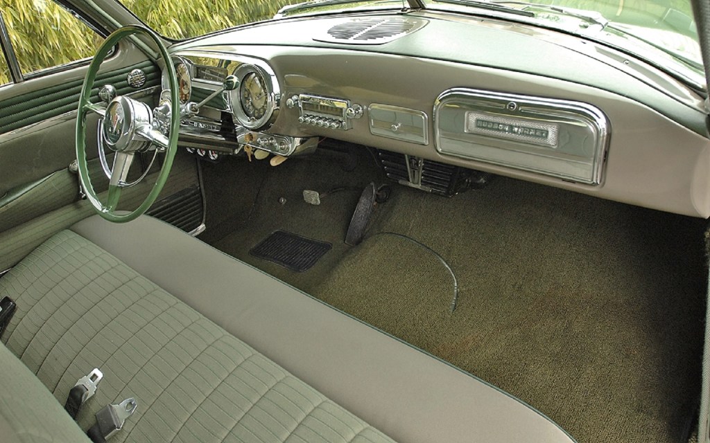 The green-and-tan front bench seat and dashboard of a 1952 Hudson Hornet Twin-H Power