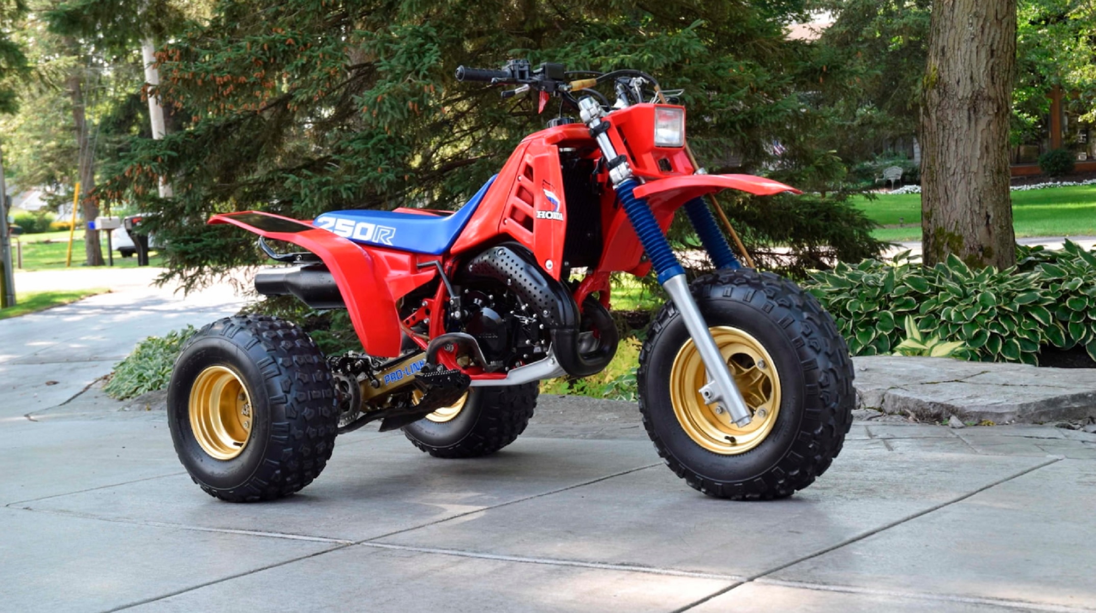 A red 1985 Honda ATC 250R with a blue seat on a driveway