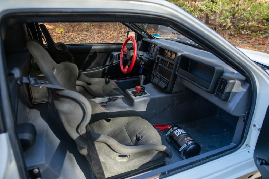 The Sparco seats, red steering wheel, and dashboard of a 1986 Ford RS200 Evolution