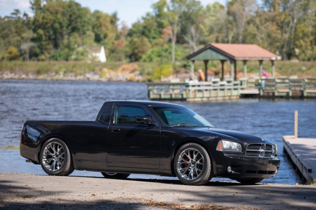 a black 2006 Dodge Charger Ute conversion parked next to a lake