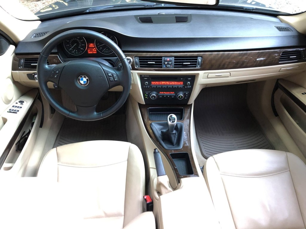 An overhead view of a 2011 BMW 328i Sports Wagon's beige-leather front seats, walnut trim, and black dashboard