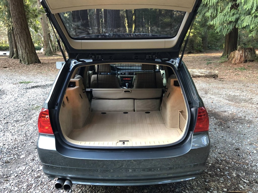 The rear view of a dark-green 2011 BMW 328i Sports Wagon's beige-leather interior with its rear seats folded