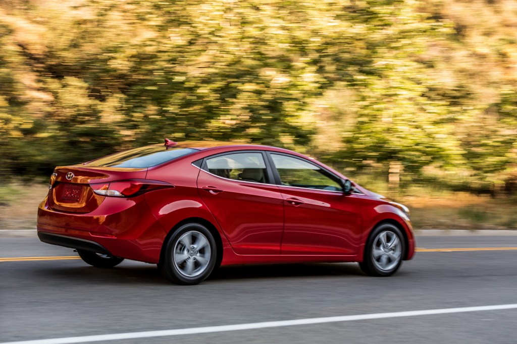 A red 2016 Hyundai Elantra driving down a highway road