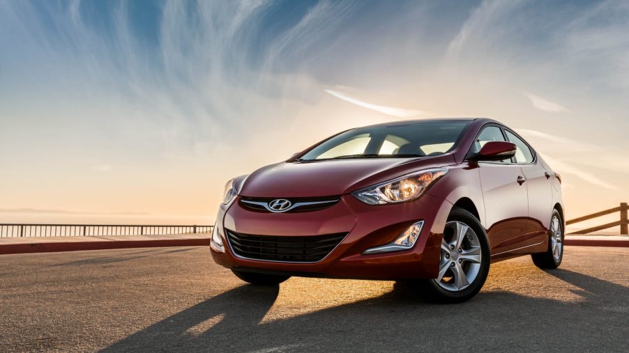 A red 2016 Hyundai Elantra on display in front of a colorful sky