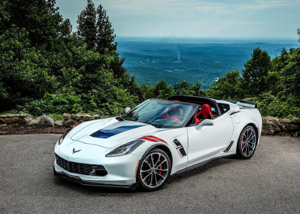 A white 2017 Chevrolet Corvette Grand Sport Convertible with red seats on a forested mountain road